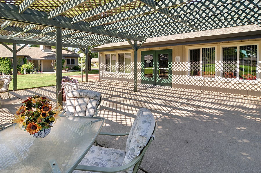 a pergola with a table and chairs in front of a house