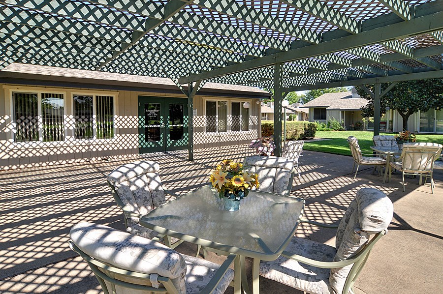 a pergola with a table and chairs in front of a house
