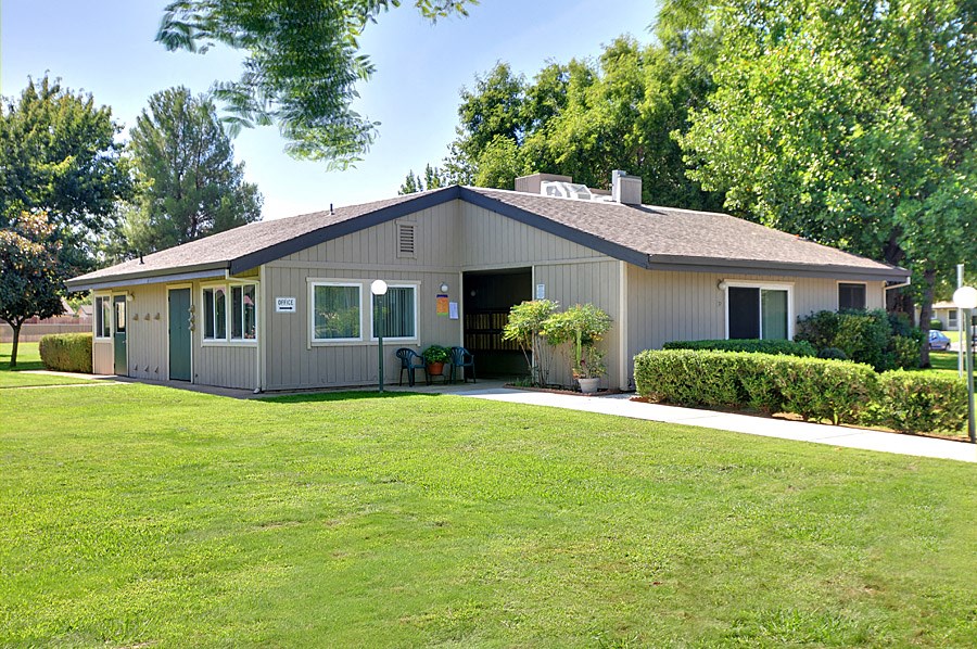 a home with a green lawn and trees in the background
