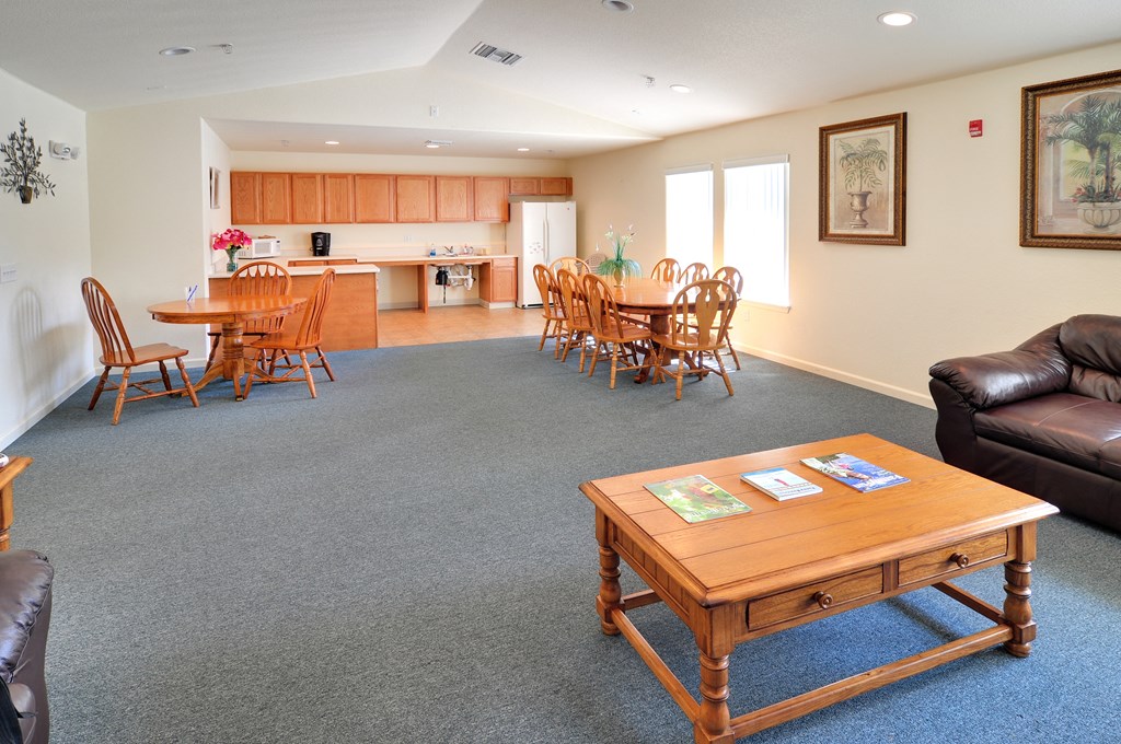 a living room with a couch a table and chairs and a kitchen in the background