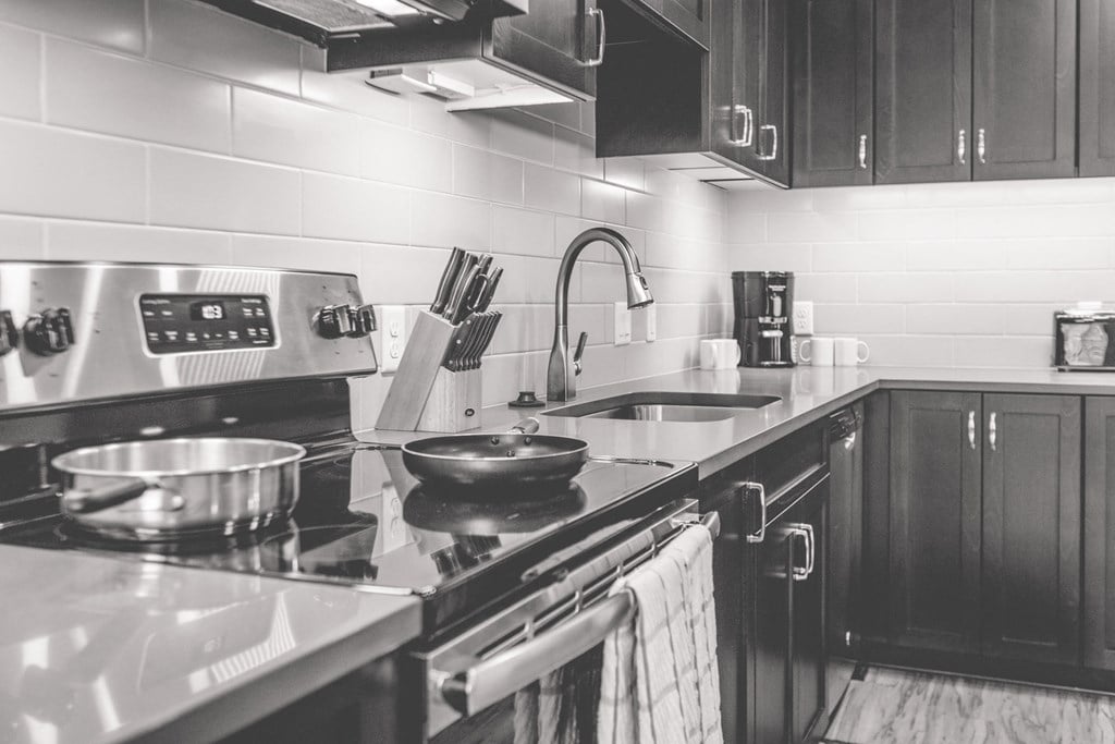 a black and white photo of a kitchen with a stove and sink