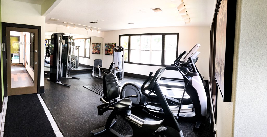 a gym with cardio equipment and windows in a hotel room