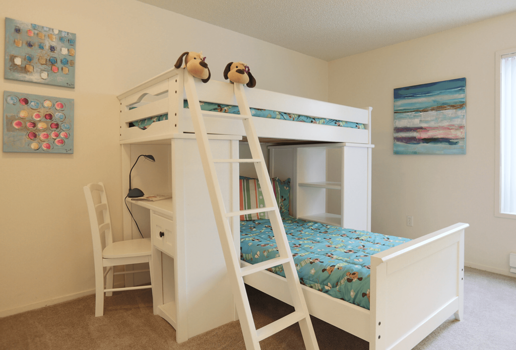 a bedroom with a bunk bed and a desk with a chair