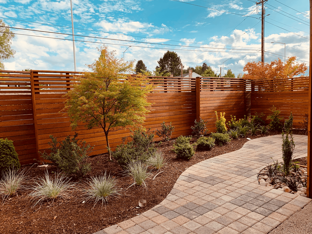 a garden with a wooden fence and a pathway