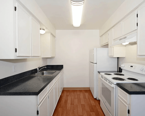 A kitchen with white cabinets and black countertops.