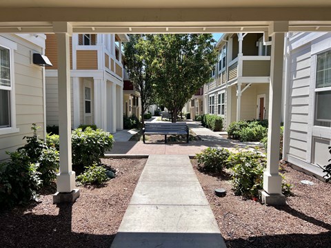 A walkway leads between two rows of white and beige houses.