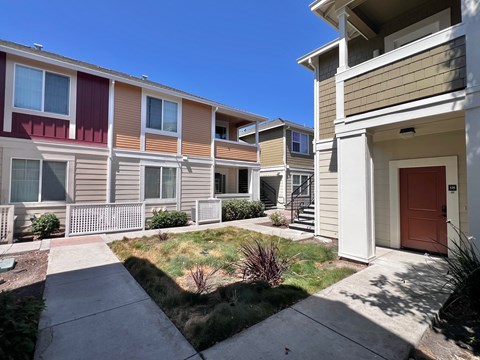A row of townhouses with a sidewalk in front.