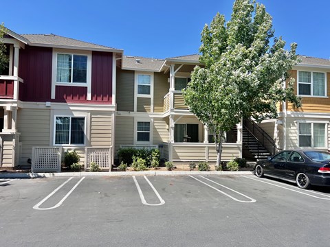 A black car is parked in a parking lot in front of a building.