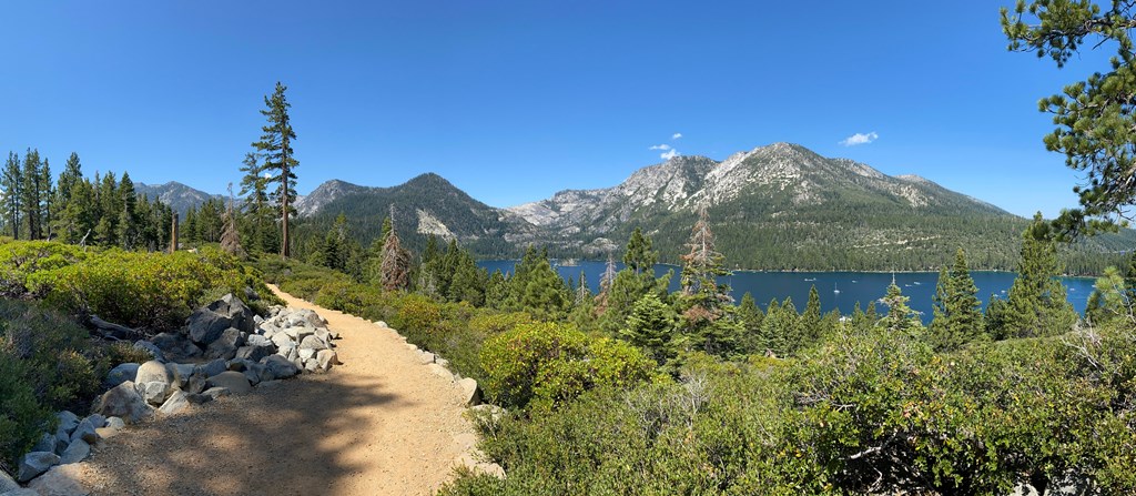 a dirt trail with a lake and mountains in the background