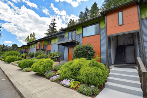 A row of modern townhouses with green bushes in front.