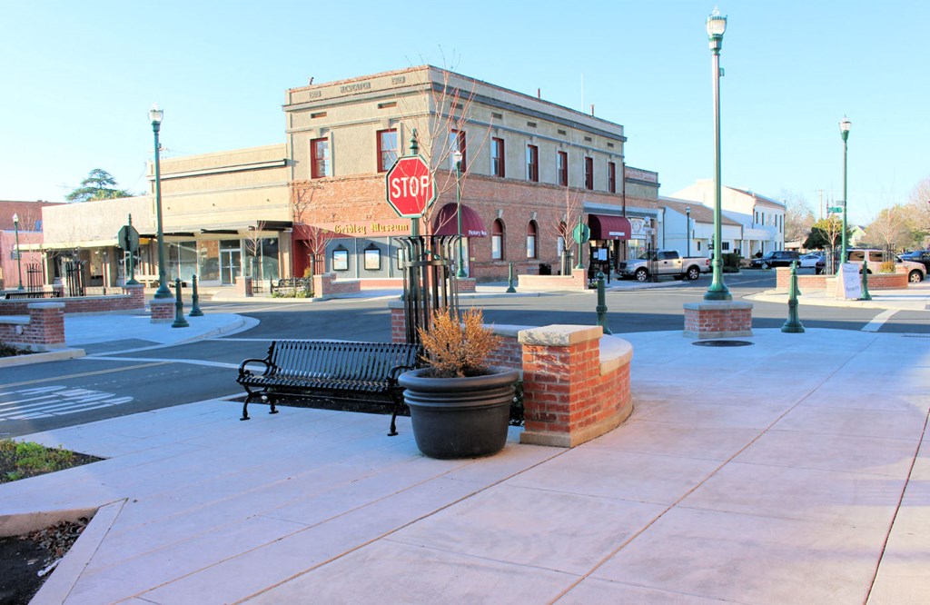 a stop sign on a sidewalk next to a bench