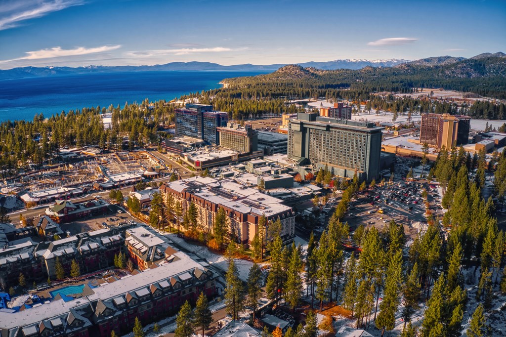 an aerial view of a city with a lake and mountains in the background