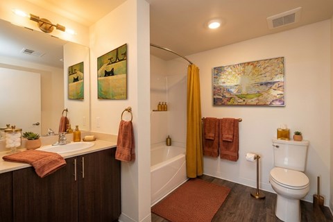 A bathroom with a toilet, sink, and a painting on the wall.
