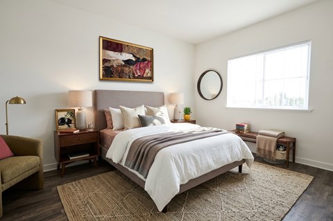 A bedroom with a large bed and a painting on the wall.
