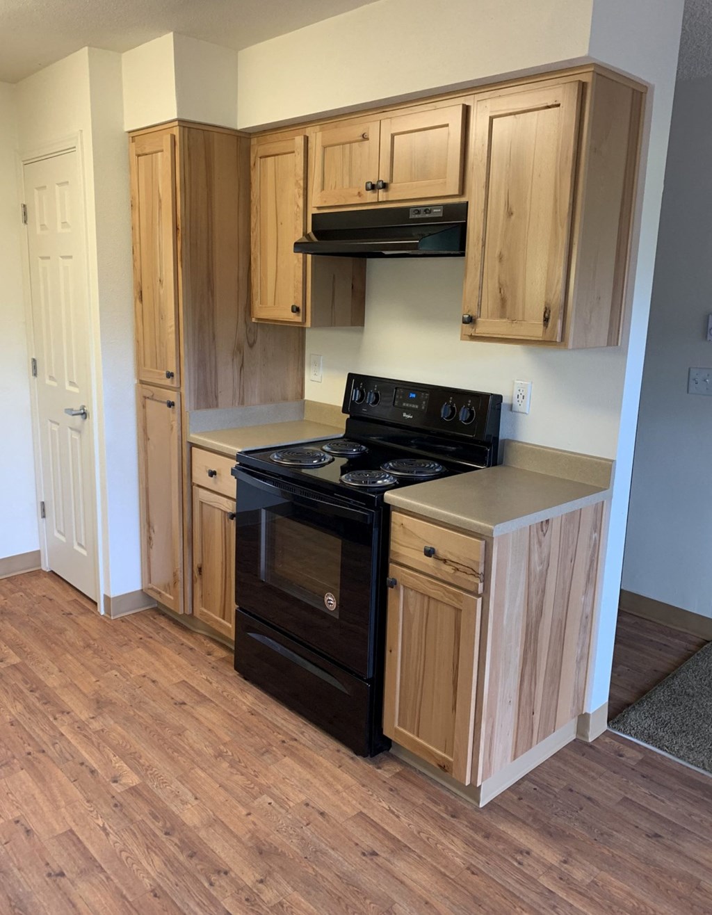 an empty kitchen with wooden floors and a black stove and oven