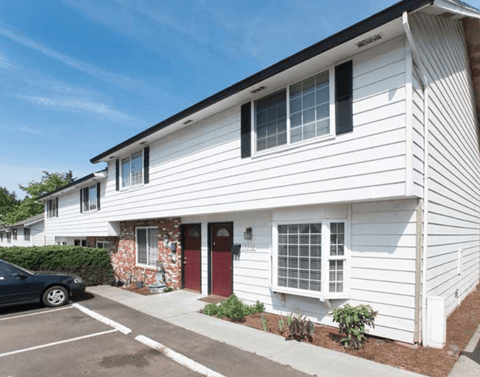 a white house with a red door and a parking lot