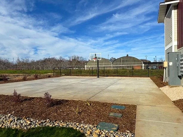 A large, empty parking lot with a fence and a building in the background.