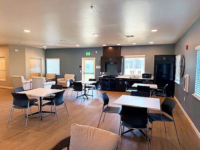 A room with a white table surrounded by black chairs.
