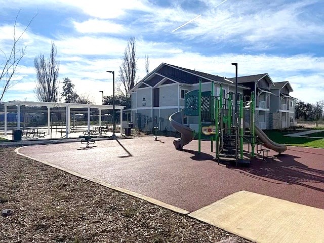 A playground with a slide, swings, and a seesaw.
