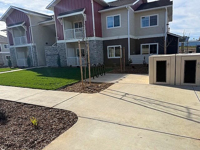 A row of houses with a concrete walkway in front.