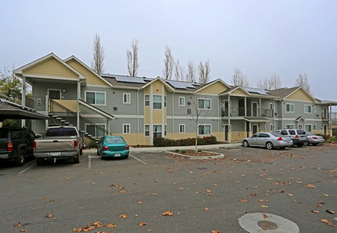 a row of apartment buildings with cars parked in a parking lot