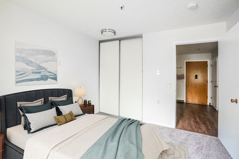 A bedroom with a bed, nightstand, and a painting on the wall.