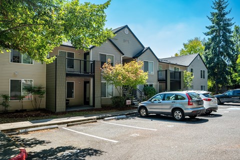 A silver car is parked in a parking lot in front of a building.