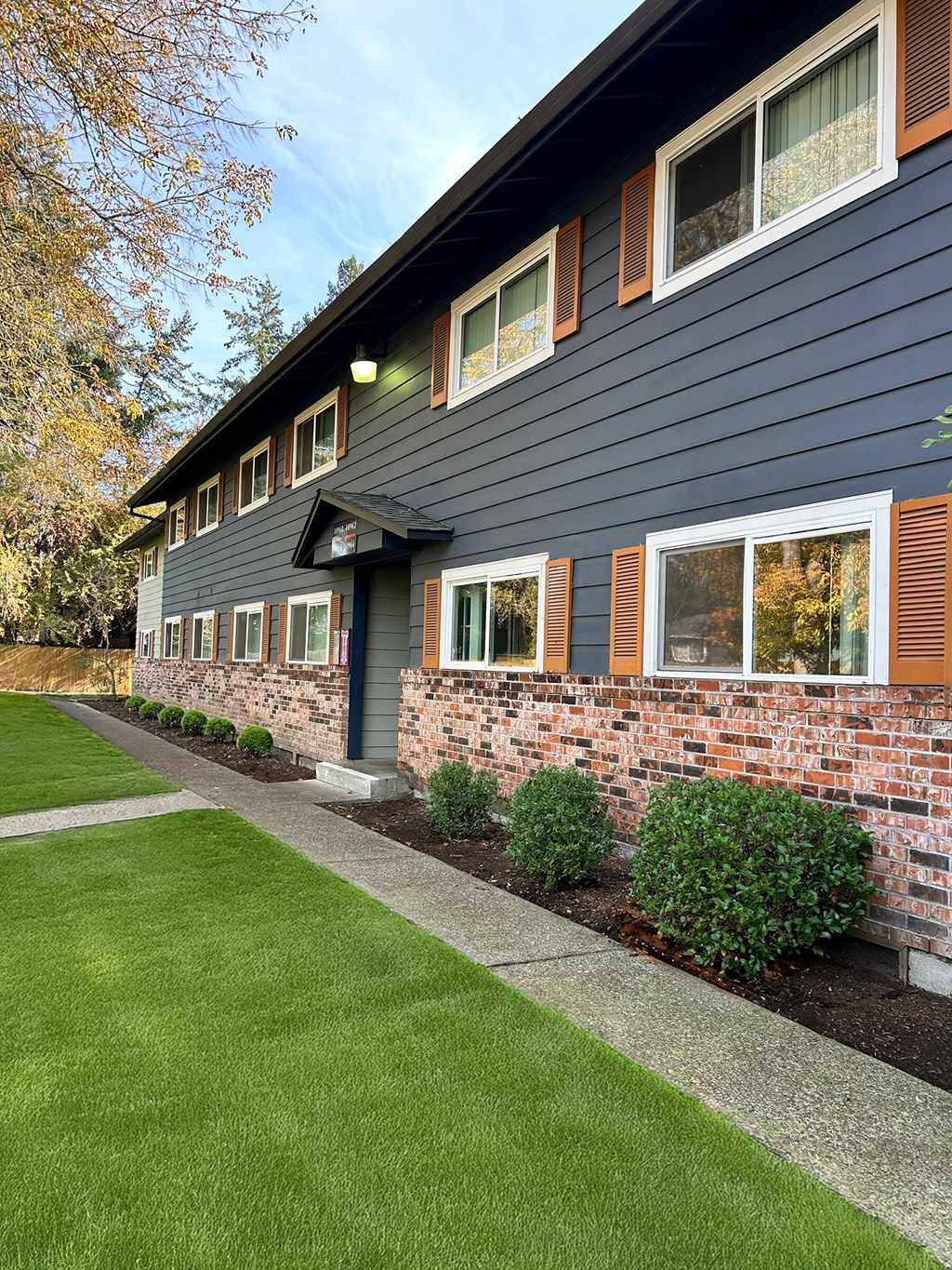 A house with a grey siding and a brick wall.