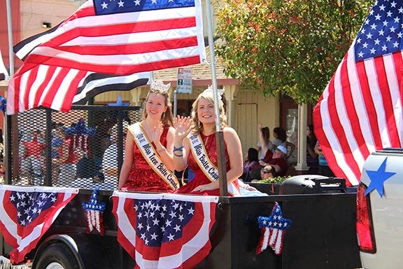 two women riding in a parade with an flag