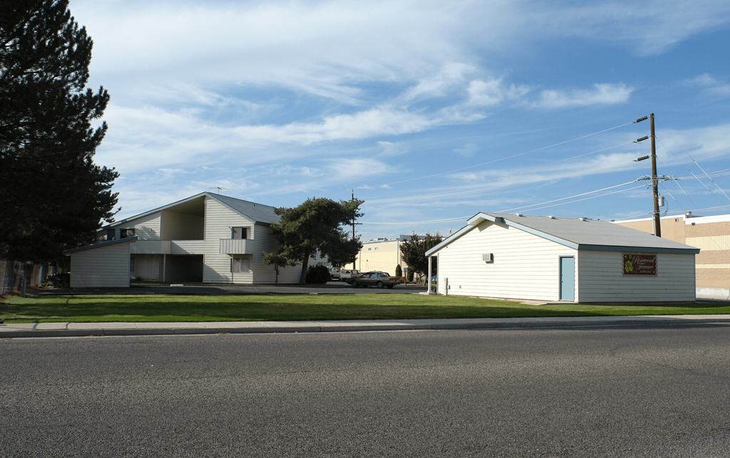 A white house with a blue door is situated on a street.