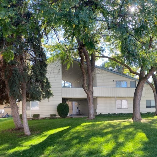 A house with a green lawn and trees in front.