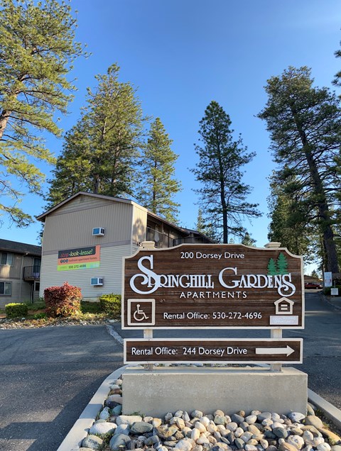 a sign for sonchi gardening apartments in front of a building