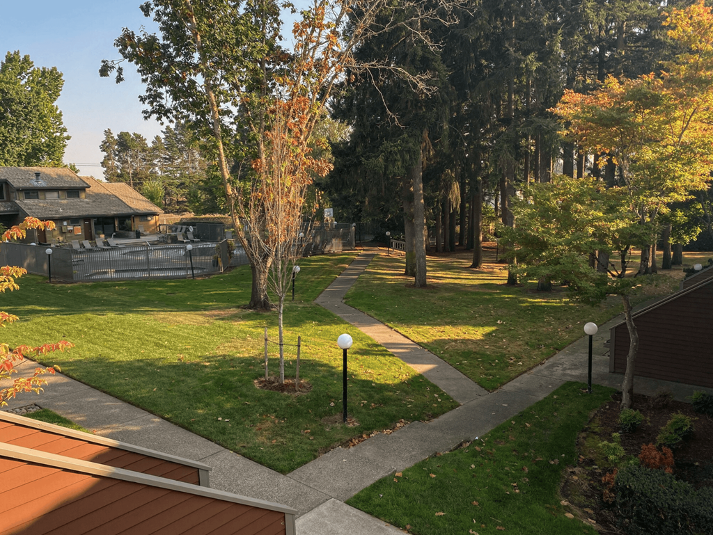 a walkway through a park with trees and buildings in the background