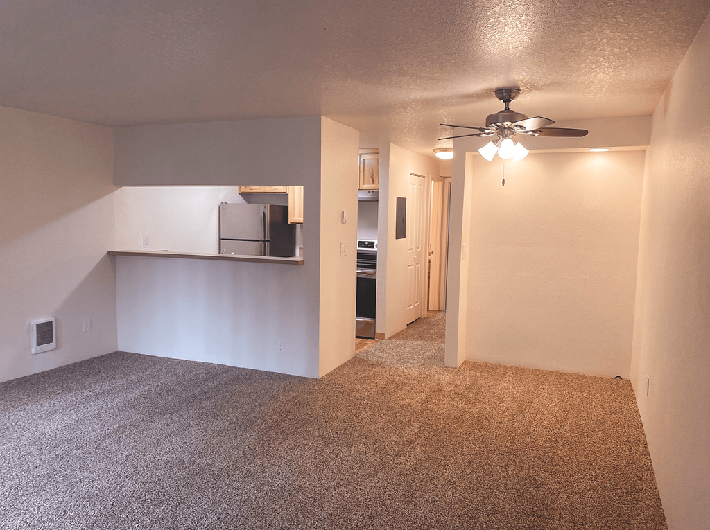 an empty living room with a ceiling fan