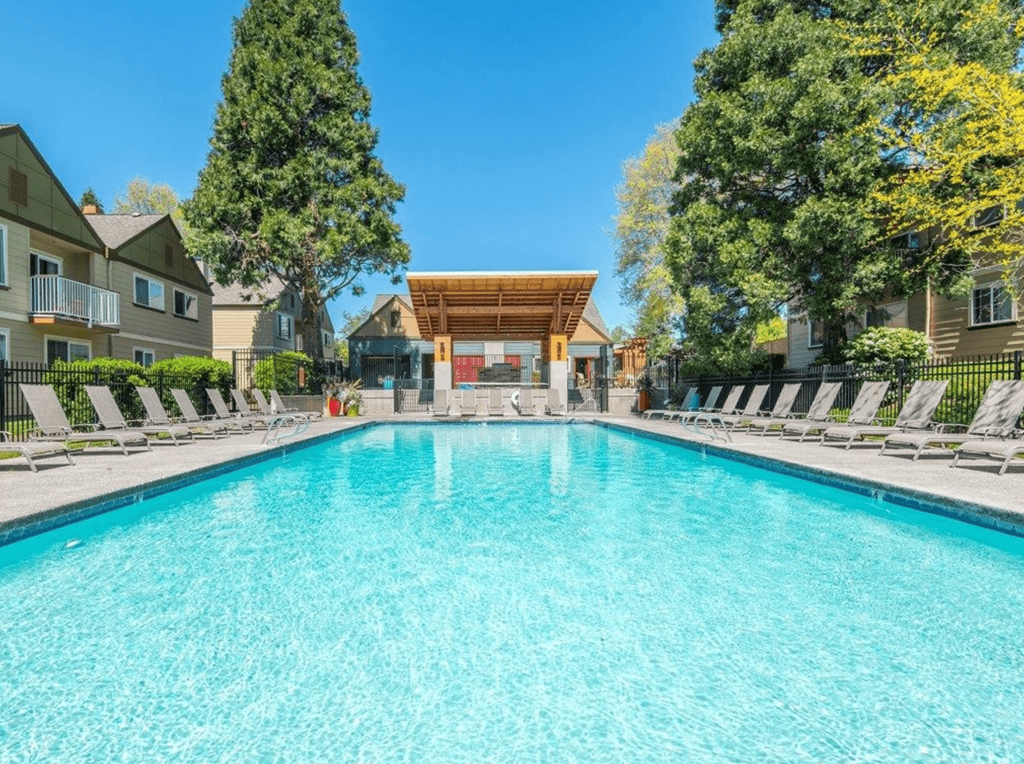 a swimming pool with chaise lounge chairs and a clubhouse in the background
