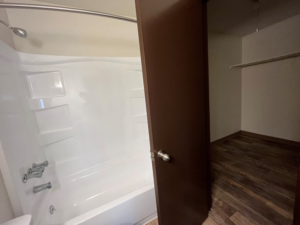 an open door leading into a bathroom with a shower and a toilet