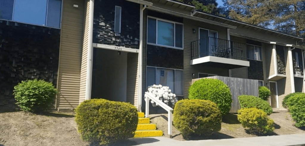 an apartment building with yellow steps and a wooden fence