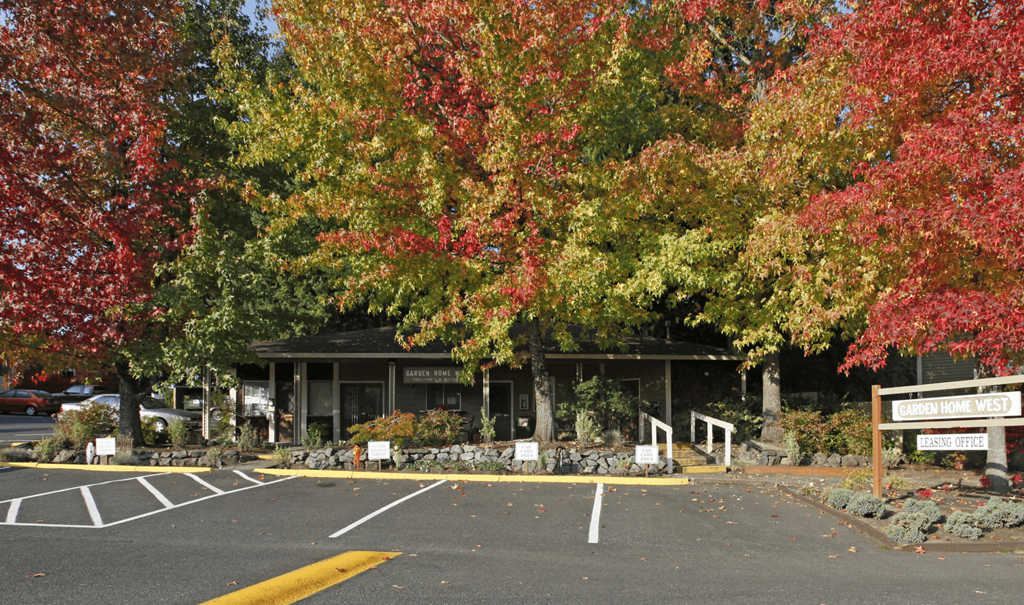 an empty parking lot with trees in front of a building