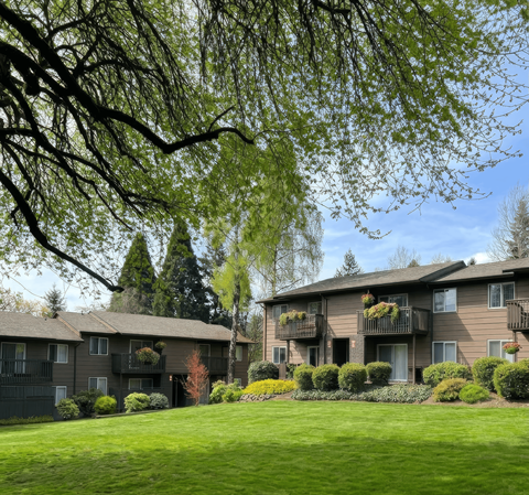 Apartment complex with green lawn and trees.