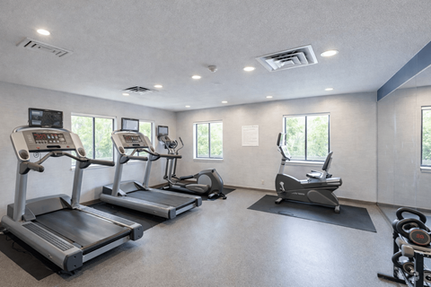 A gym with treadmills, elliptical machines, and a stationary bike.