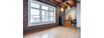 an empty living room with a large window and a kitchen