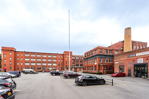 A parking lot with cars and a building with a sign that says "Motorcycle" in the background.