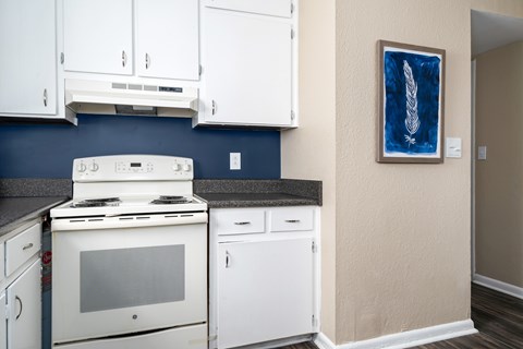 A kitchen with white cabinets and a blue backsplash.