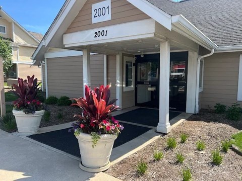 A building with the number 2001 on it has a red plant in a white pot in front of it.