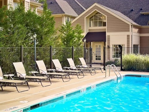 A row of lounge chairs are set up by a pool.
