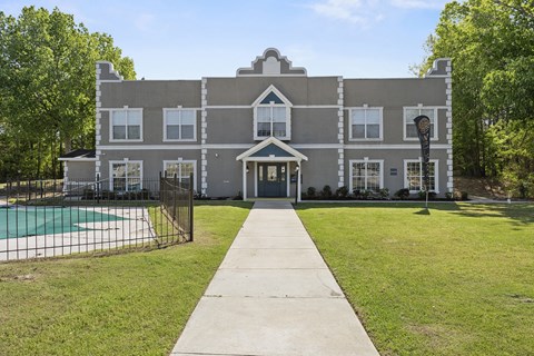 A grey building with a pool in front.