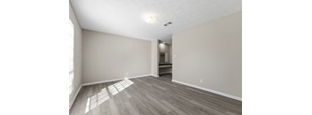 A room with light wood flooring and white walls.