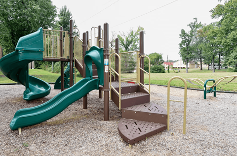 A playground with a green slide and a brown wooden structure.