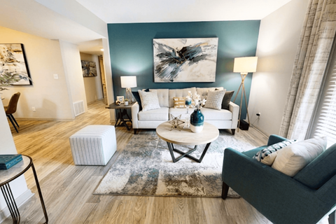 A living room with a white couch, a coffee table, and a large abstract painting on the wall.