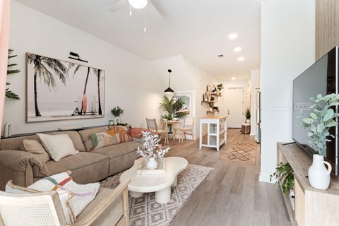 A living room with a couch, a coffee table, and a painting of a palm tree on the wall.